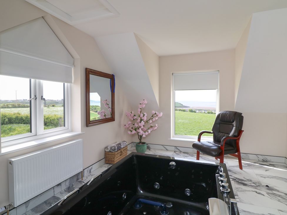 A bathroom with a bathtub and a chair at Ard Uisce @ Estuary Bliss, Duncannon, County Wexford