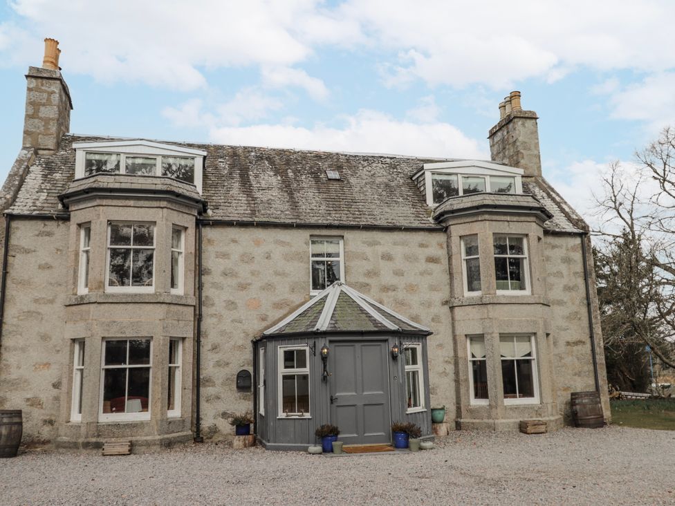 A house with a gravel driveway and planters at Achnagonlin House in Grantown-on-Spey