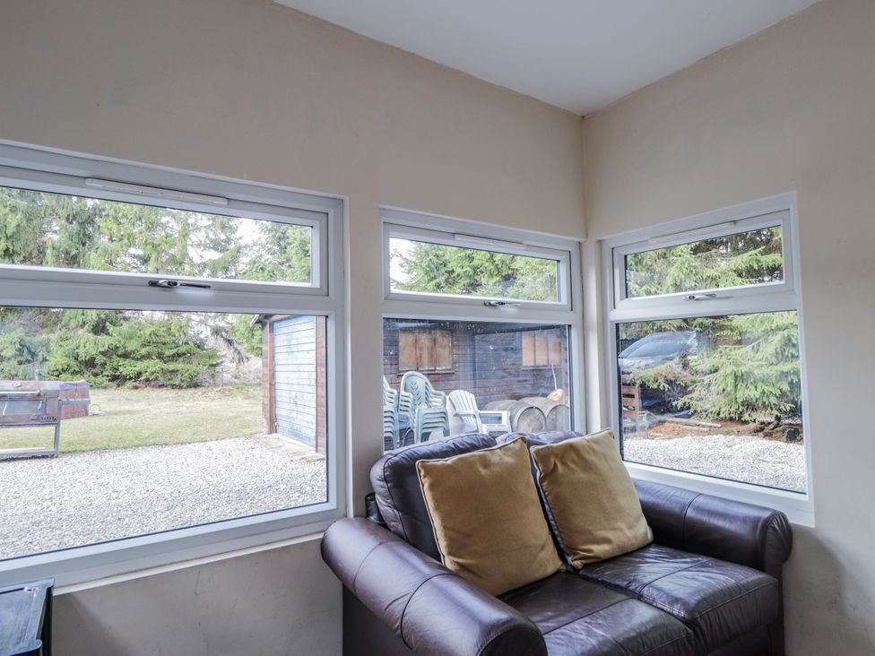 A sunroom with a couch and windows at Achnagonlin House in Grantown-on-Spey
