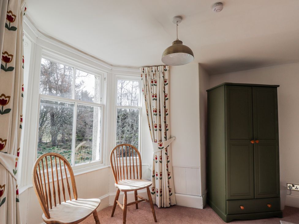 A bedroom with chairs and a wardrobe at Achnagonlin House, Grantown-on-Spey
