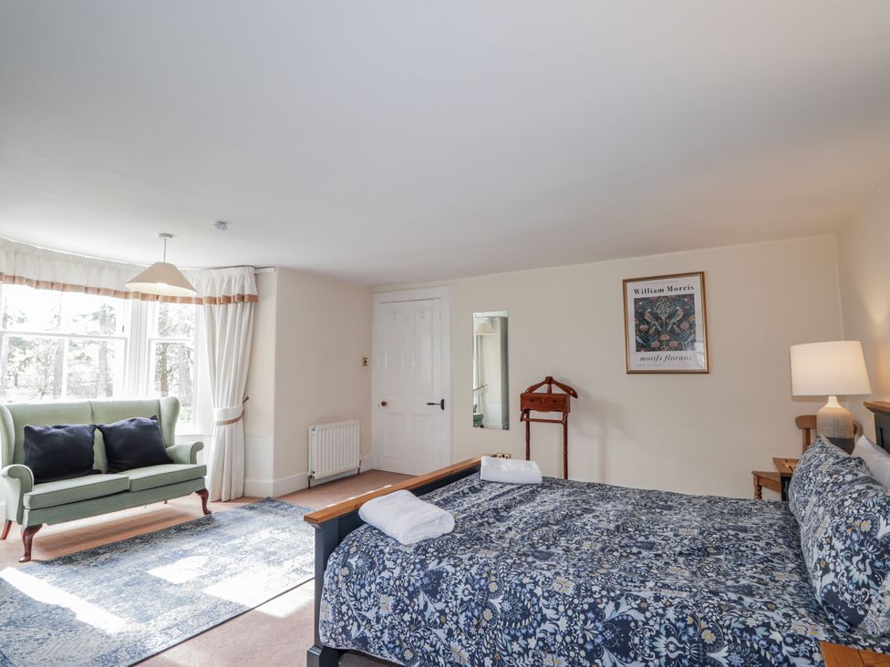 A bedroom featuring a bed, a sofa, and wall art at Achnagonlin House in Grantown-on-Spey
