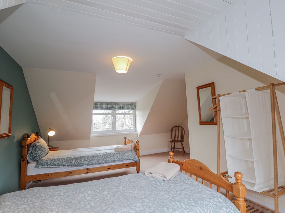 A bedroom with two beds and a chair at Achnagonlin House in Grantown-on-Spey