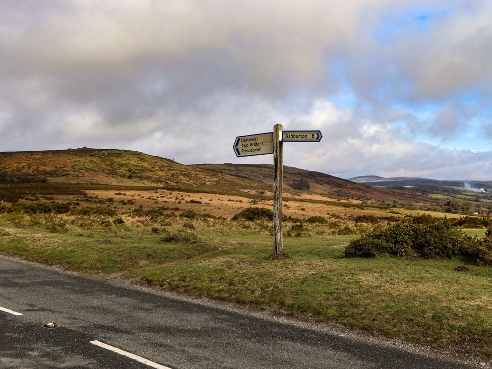 A signpost directing to Dartmeet, Two Bridges, Princetown, and Ashburton in a rural landscape in Dartmoor