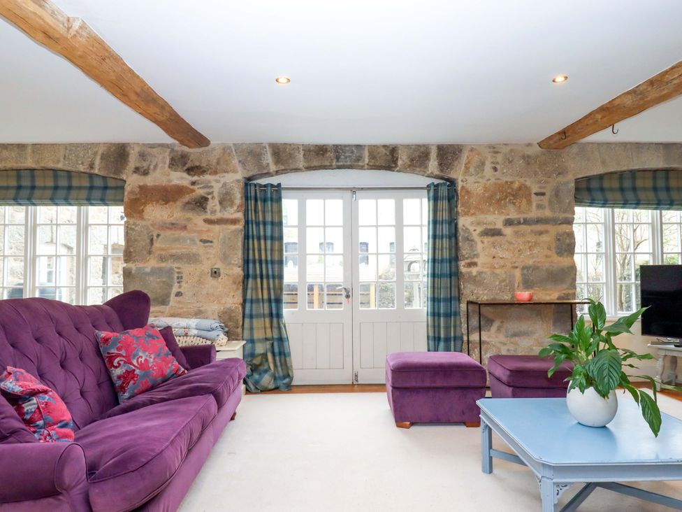 A living room with a purple sofa and table at The Mill House in Newton Abbot