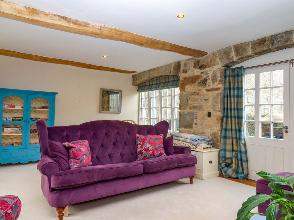 A living room with a purple sofa and a blue bookshelf at The Mill House in Newton Abbot