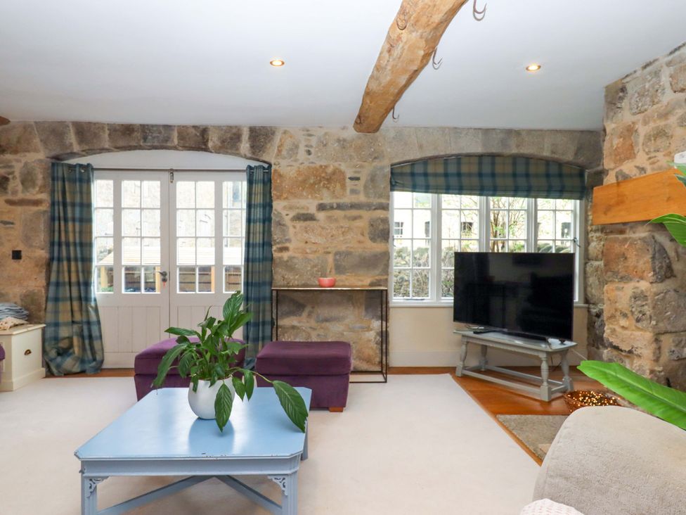 A living room with a television and sofa at The Mill House in Newton Abbot
