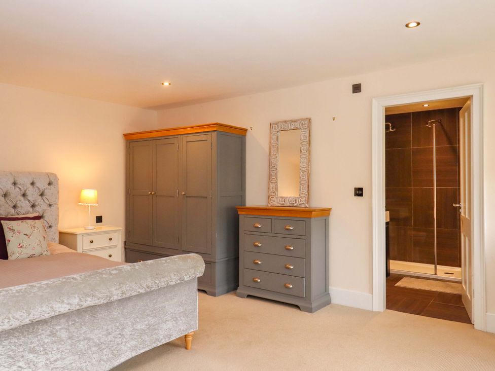 A bedroom with a bed, nightstand, wardrobe, and shower at The Mill House in Newton Abbot