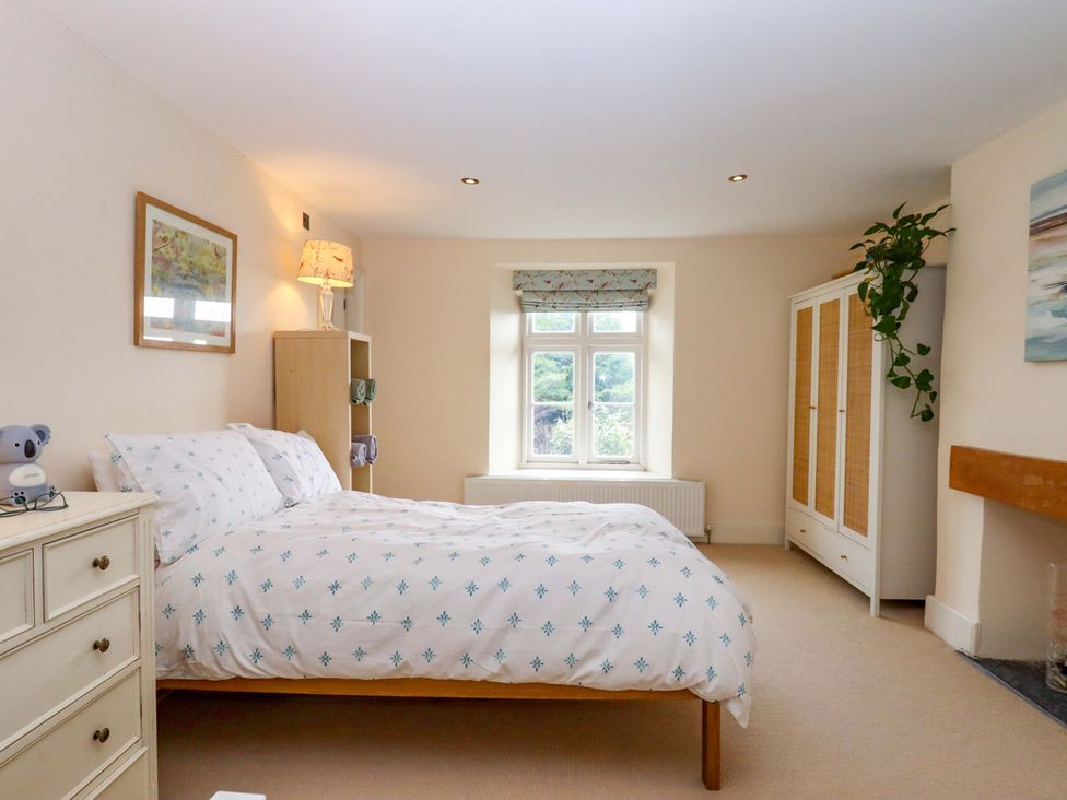 A bedroom with a bed and window at The Mill House in Newton Abbot