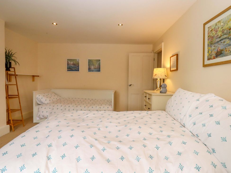 A bedroom with two beds and a bedside table at The Mill House in Newton Abbot