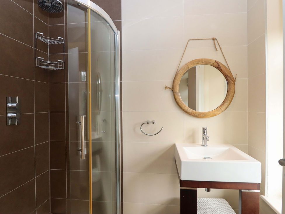A bathroom with a shower, sink, and mirror at The Mill House in Newton Abbot