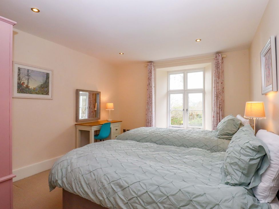 A bedroom with two beds and a desk at The Mill House in Newton Abbot