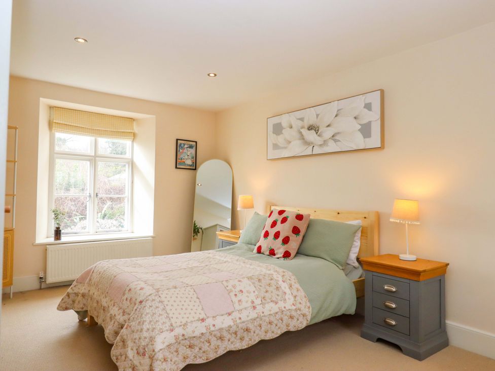 A bedroom with a bed and bedside table at The Mill House in Newton Abbot