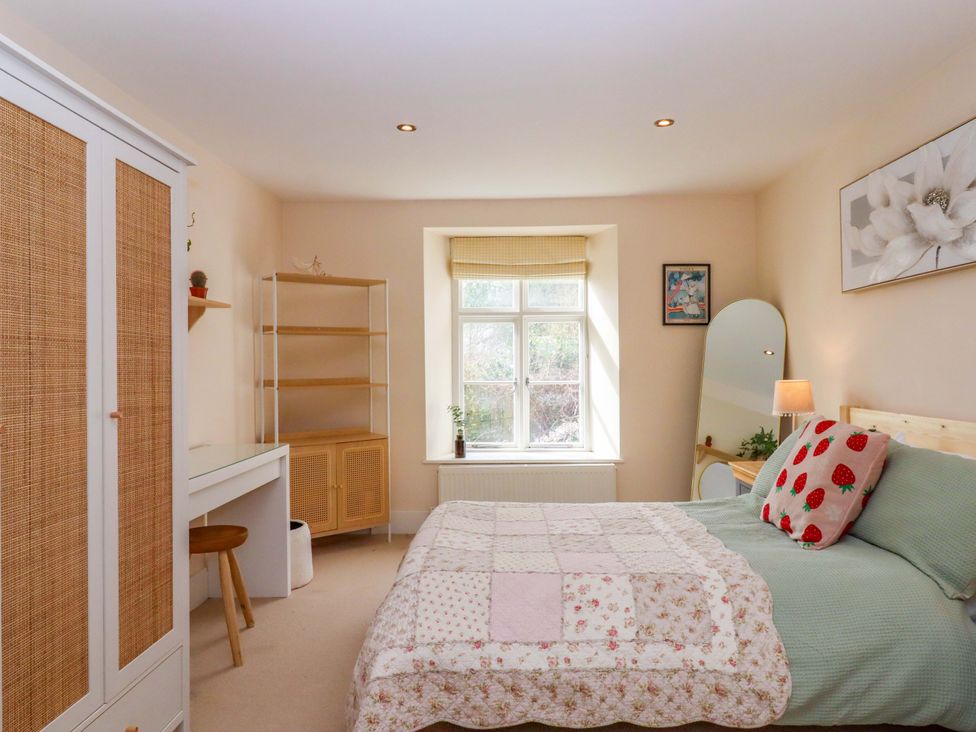 A bedroom with a bed and window at The Mill House in Newton Abbot