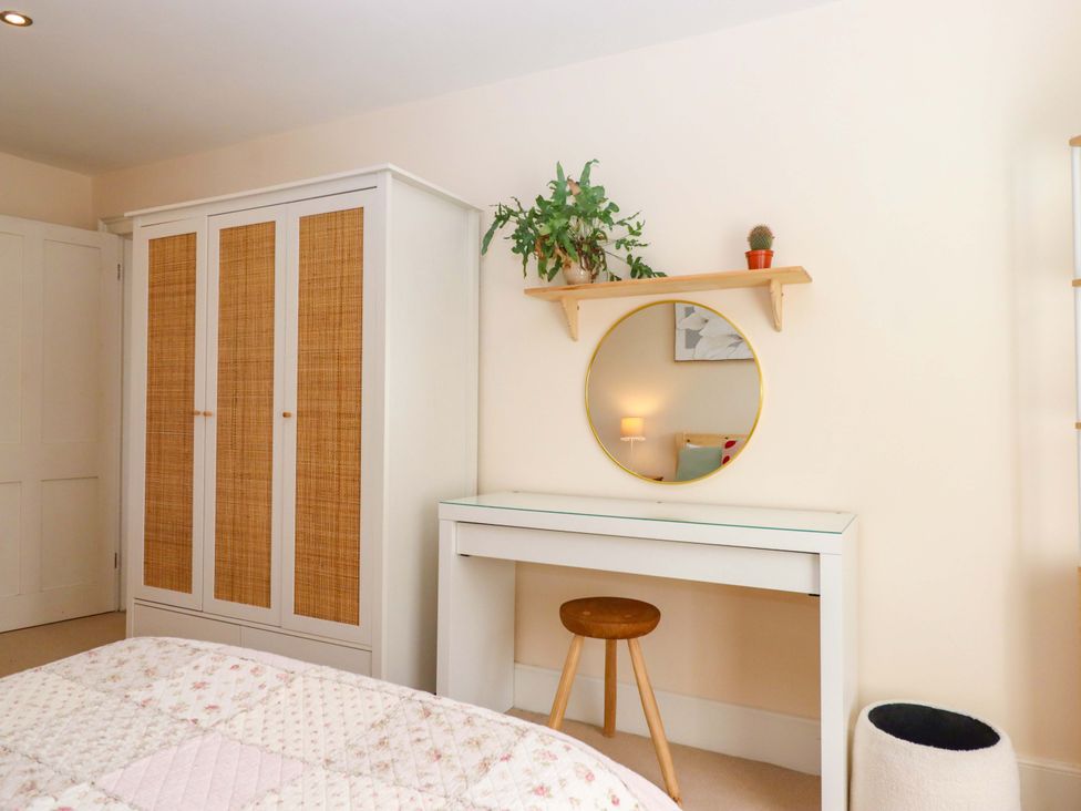 A bedroom with a wardrobe, desk, and mirror at The Mill House in Newton Abbot