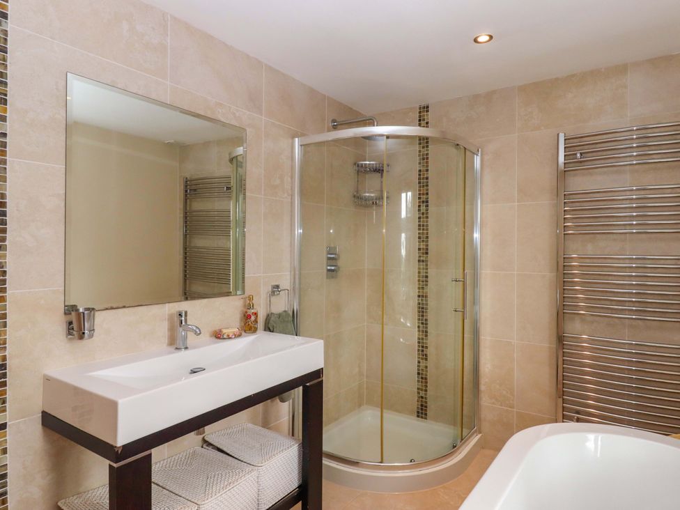 A bathroom with a shower, bathtub, and sink at The Mill House in Newton Abbot