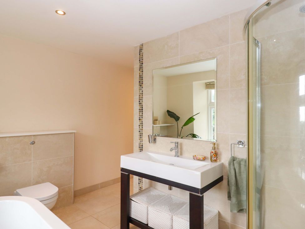 A bathroom with a sink, toilet, and shower at The Mill House in Newton Abbot