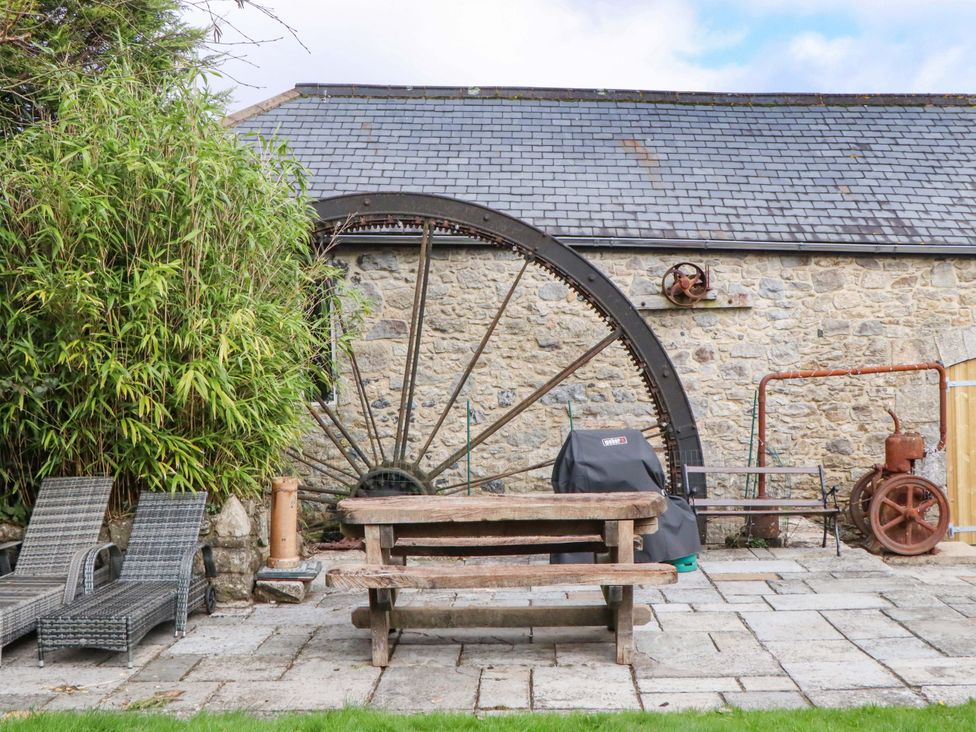 A garden with a stone wall and a table with chairs at The Mill House in Newton Abbot