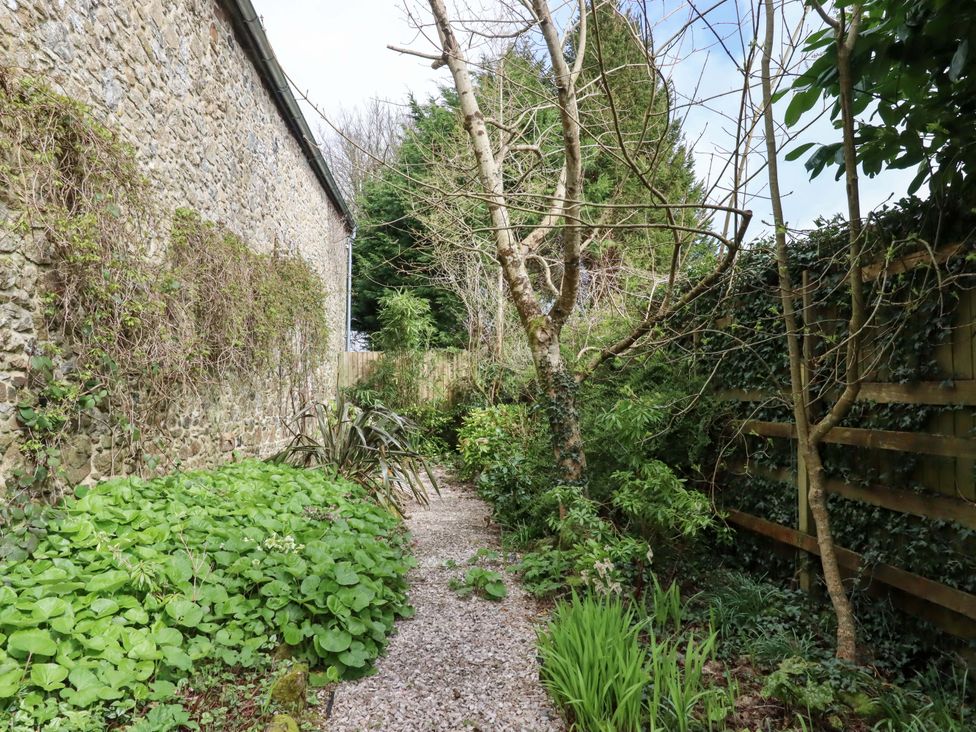 A garden with a gravel path and stone wall at The Mill House in Newton Abbot