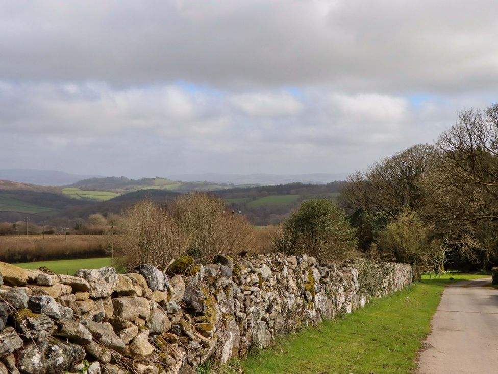 A stone wall along a road with hills and trees at The Mill House in Newton Abbot