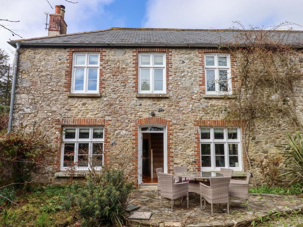 A house with a stone exterior and patio furniture at The Mill House in Newton Abbot
