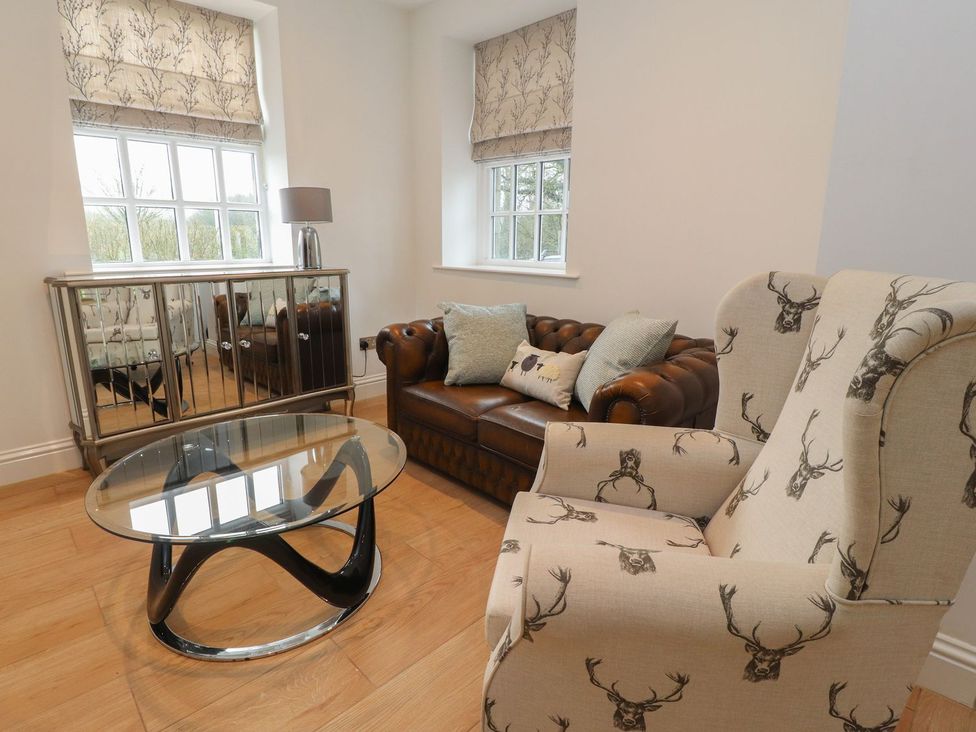 A living room with a sofa and a glass coffee table at The Lodge House in Dolphinholme near Galgate