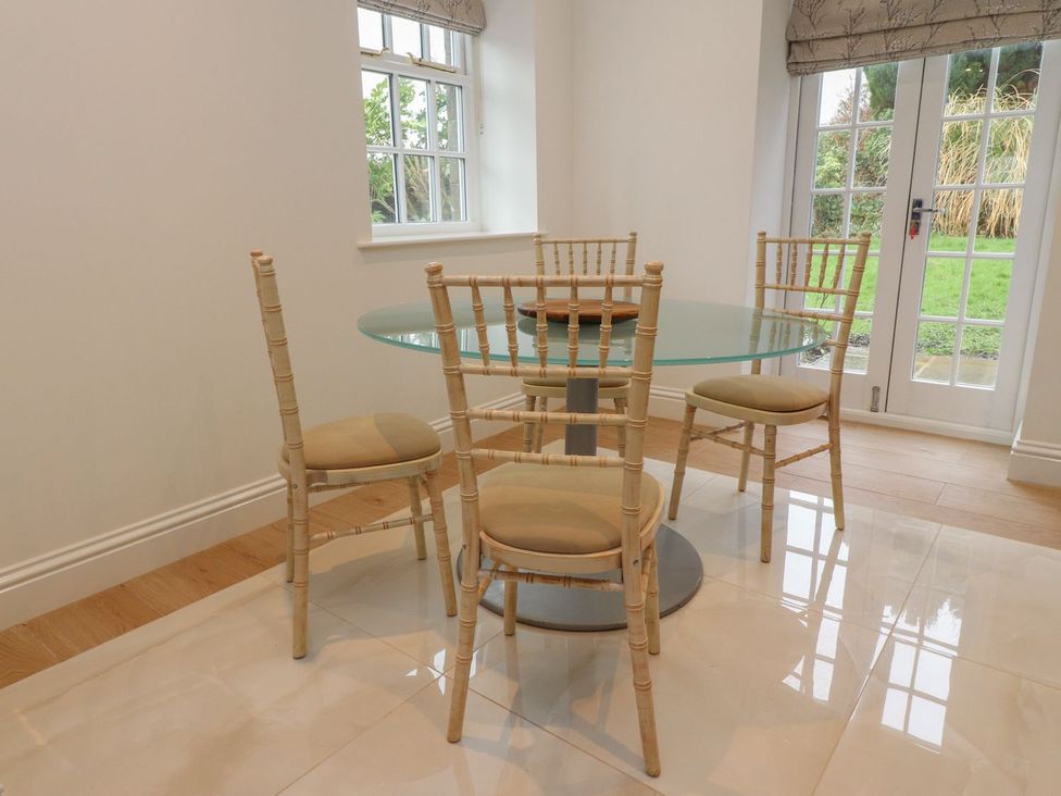 A dining room with a glass table and four chairs at The Lodge House in Dolphinholme near Galgate