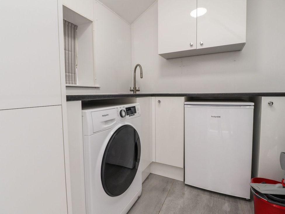 A laundry room with a washing machine and a fridge at The Lodge House in Dolphinholme near Galgate