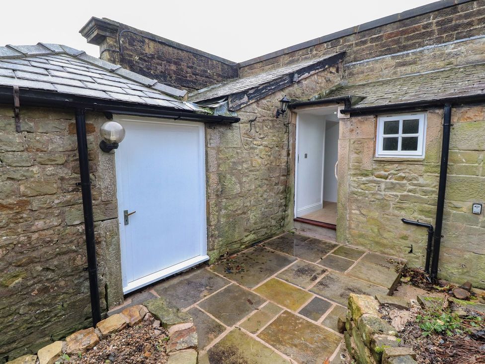 An outdoor area with stone pathway and a white door at The Lodge House Dolphinholme near Galgate