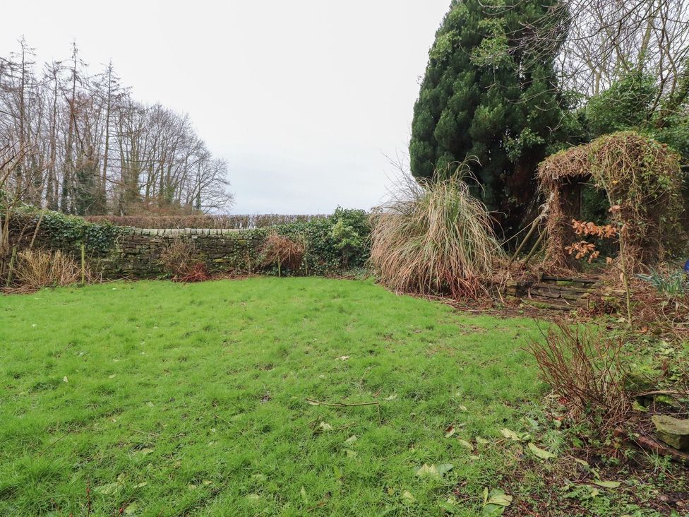 A garden with grass, trees, and a decorative archway at The Lodge House in Dolphinholme near Galgate