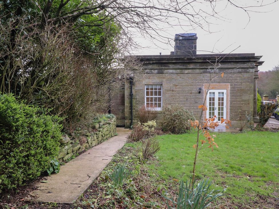 An exterior view of a house with a pathway surrounded by plants at The Lodge House in Dolphinholme near Galgate