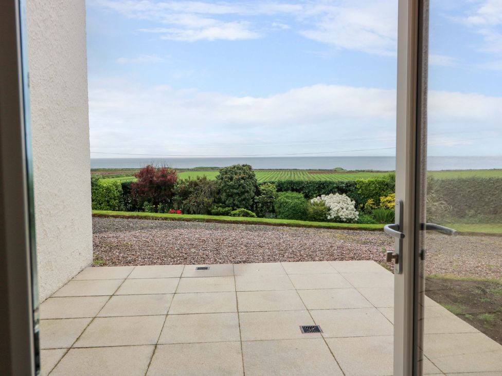 A patio view overlooking a garden and sea at Burnside Bothy near Girvan