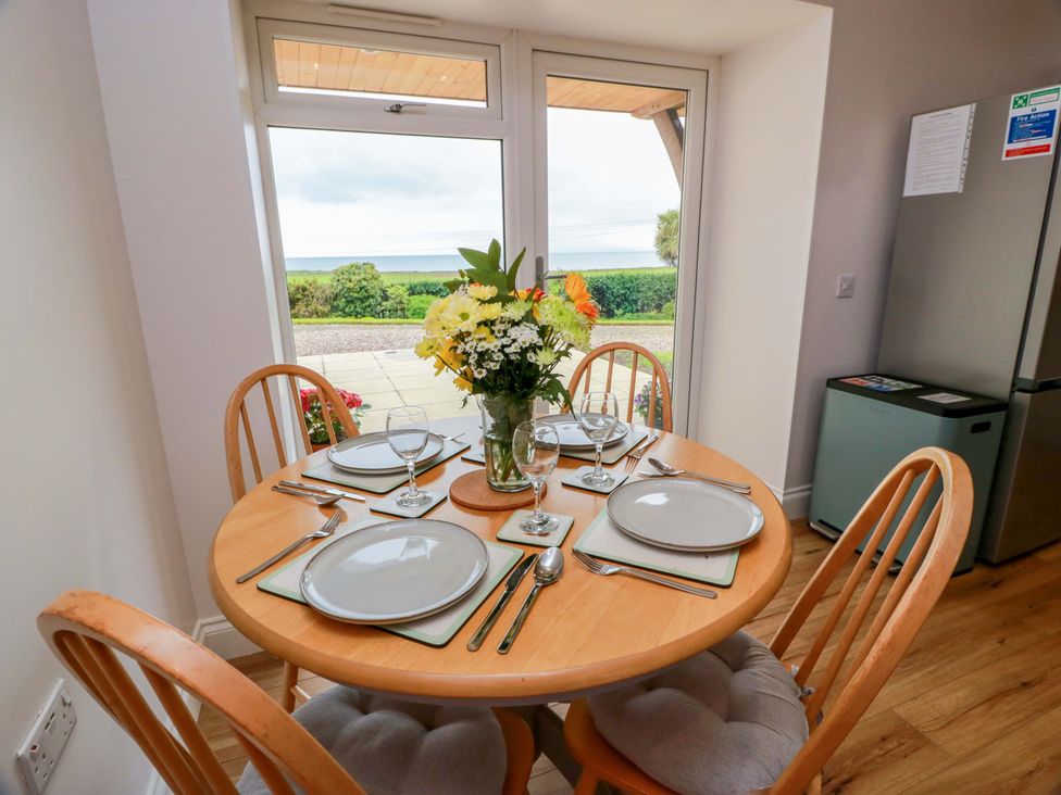 A dining room with a round table and chairs at Burnside Bothy near Girvan
