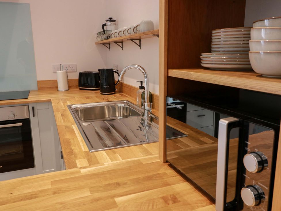 A kitchen with a sink, kettle, and microwave at Burnside Bothy near Girvan