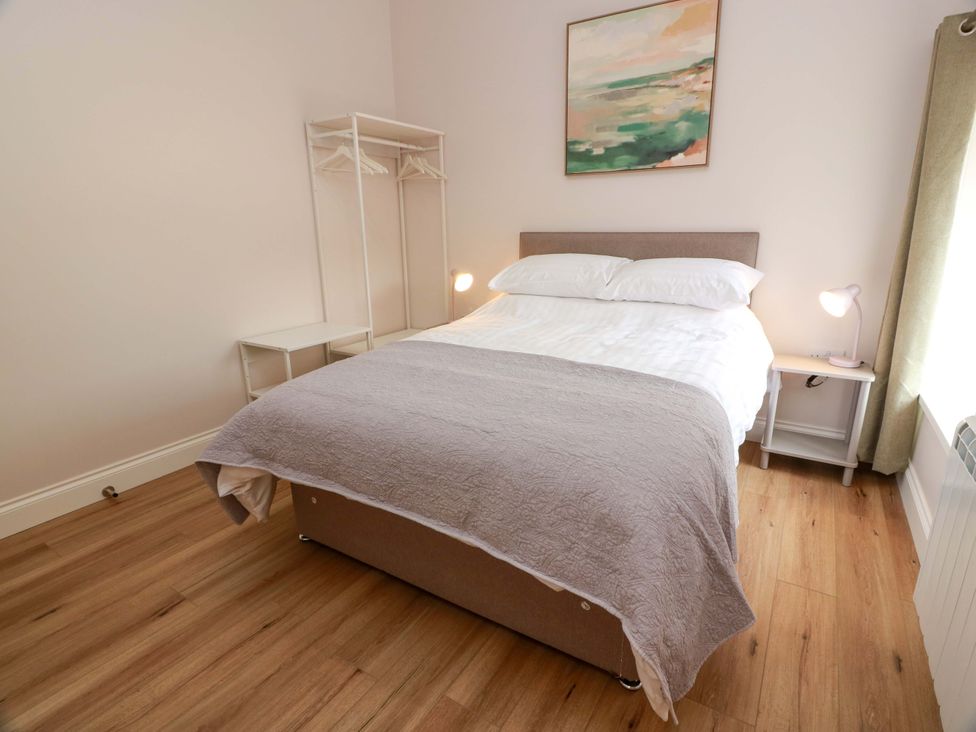 A bedroom with a bed, bedside table, and wardrobe at Burnside Bothy near Girvan