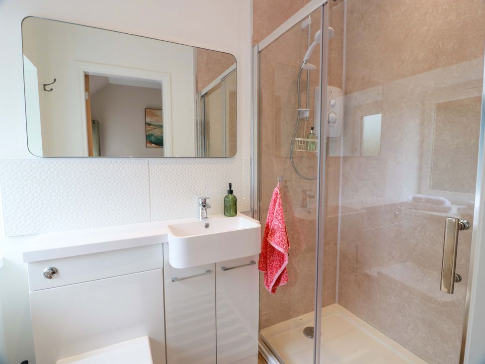 A bathroom with a sink, mirror, and shower at Burnside Bothy near Girvan