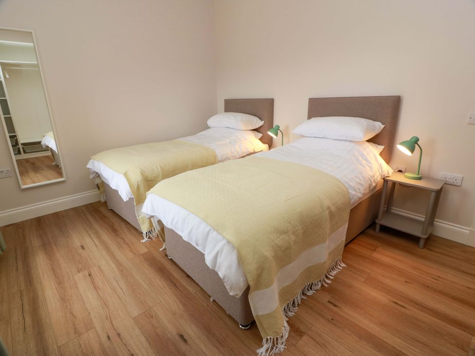 A bedroom with two single beds and a mirror at Burnside Bothy near Girvan