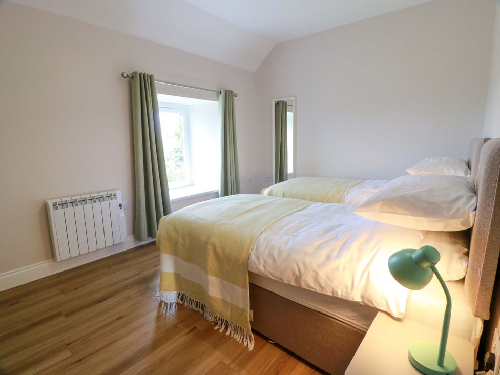 A bedroom with two beds and a desk lamp at Burnside Bothy near Girvan