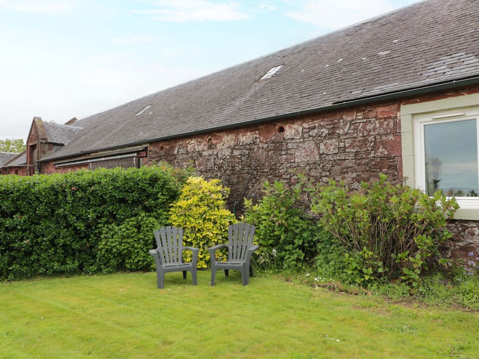 Two chairs in a garden area near a stone building at Burnside Bothy near Girvan