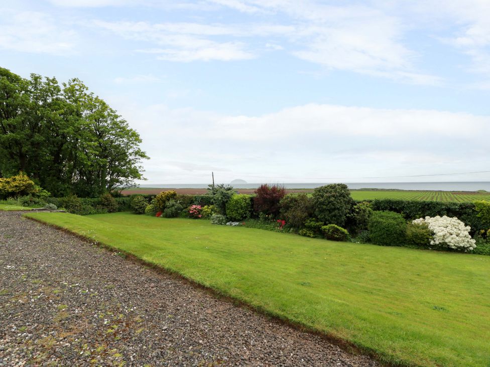 A garden with flower beds and a gravel path at Burnside Bothy near Girvan