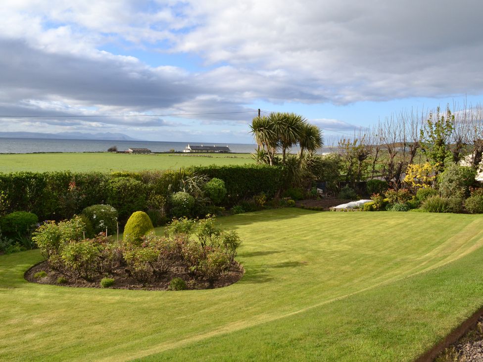 A garden with a lawn and flowers near the ocean at Burnside Bothy Burnside Farm near Girvan