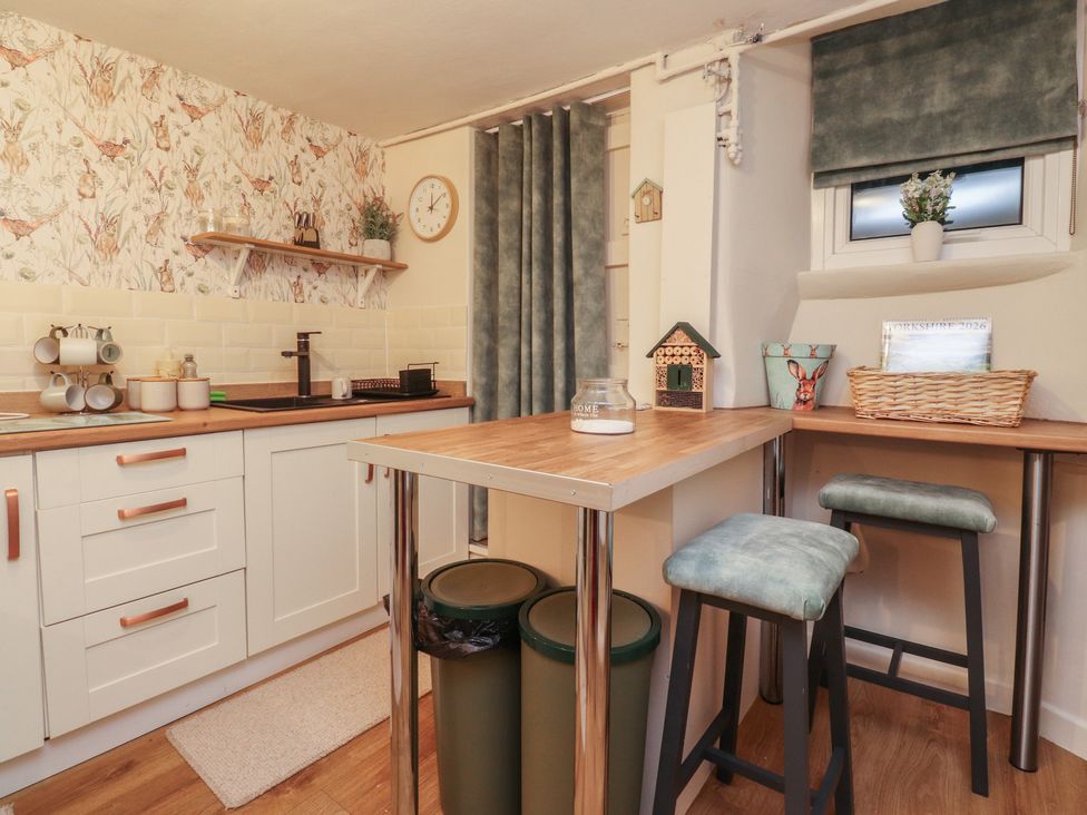 A kitchen with a counter and stools at Willow Wood in Settle