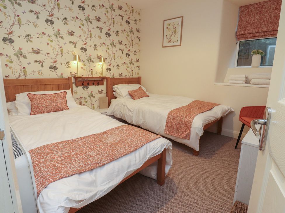 A bedroom with two beds and a chair at Willow Wood in Settle