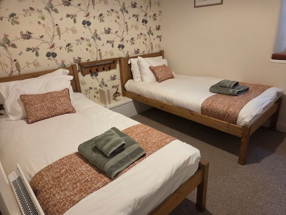A bedroom with two beds and a floral wallpaper at Willow Wood in Langcliffe near Settle