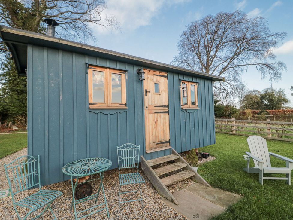 An outdoor area with a wooden shed and seating at Honeysuckle Hut, Potto Grange Farm Northallerton