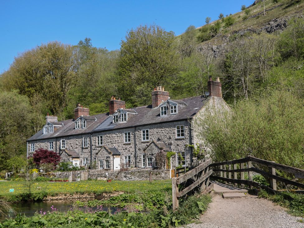 A stone house with windows and a bridge at Honeysuckle Cottage in 