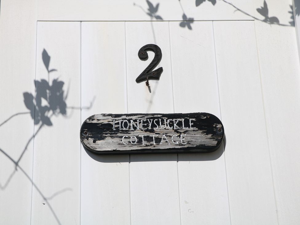 A house sign showing the number 2 and name Honeysuckle Cottage