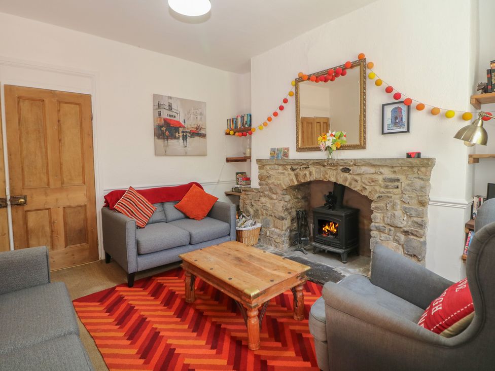 A living room with a fireplace and seating area at Honeysuckle Cottage