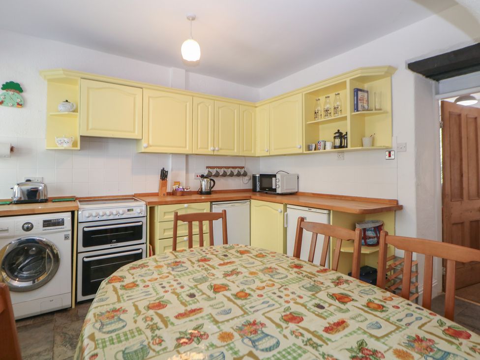 A kitchen with appliances and a dining table at Honeysuckle Cottage