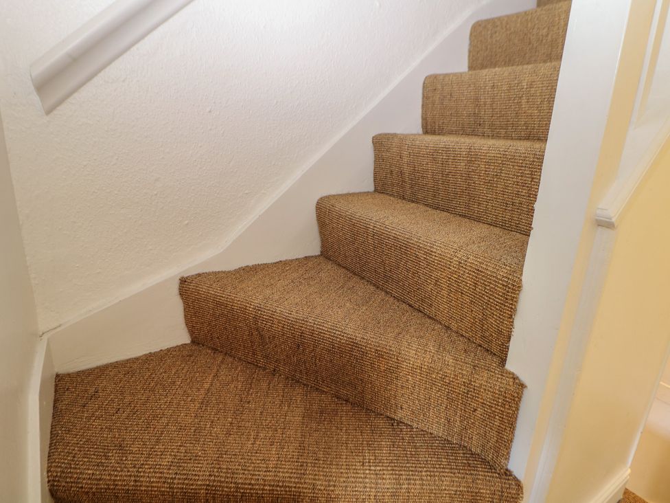 A staircase with carpeted steps at Honeysuckle Cottage