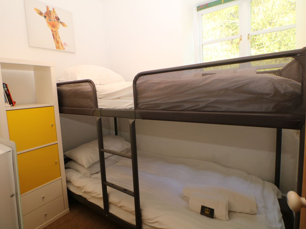 A bedroom with a bunk bed and shelf at Honeysuckle Cottage